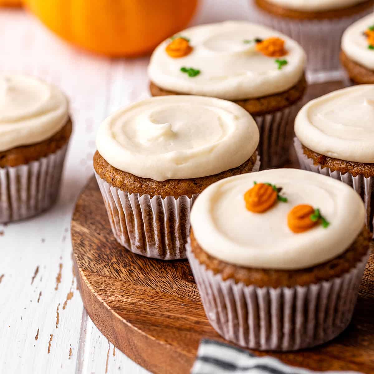 6 Pumpkin Cupcakes with cream cheese frosting on a wooden serving plate