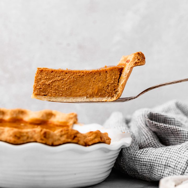 a slice of sweet potato pie being lifted out of a pie dish