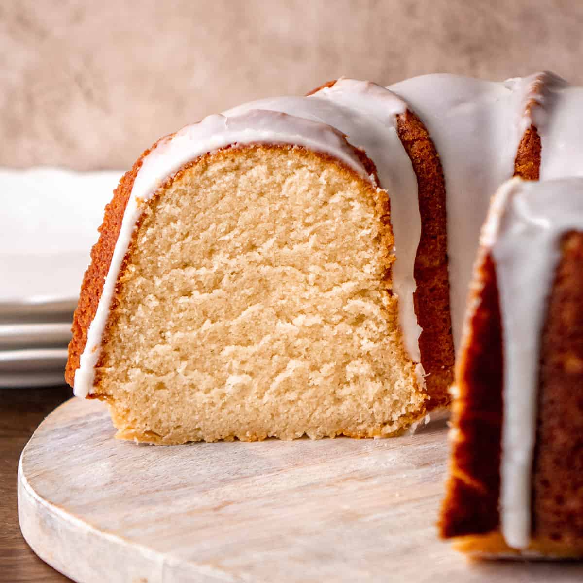 side view of a vanilla bundt cake where a piece has been cut out of it