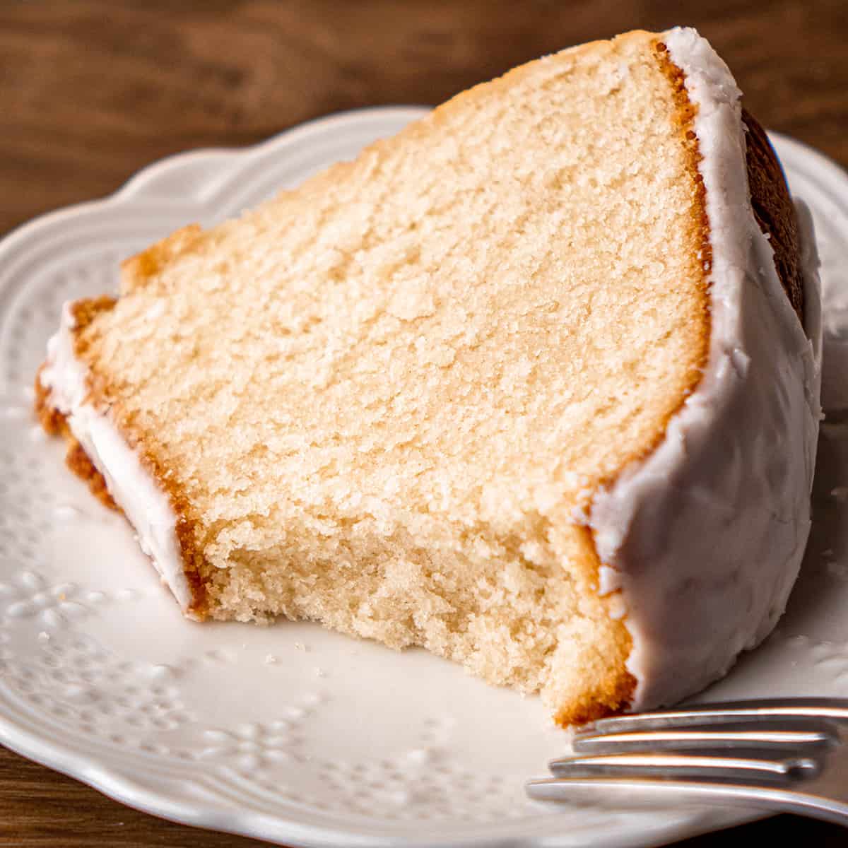 vanilla bundt cake on a plate with a bite taken out of it 