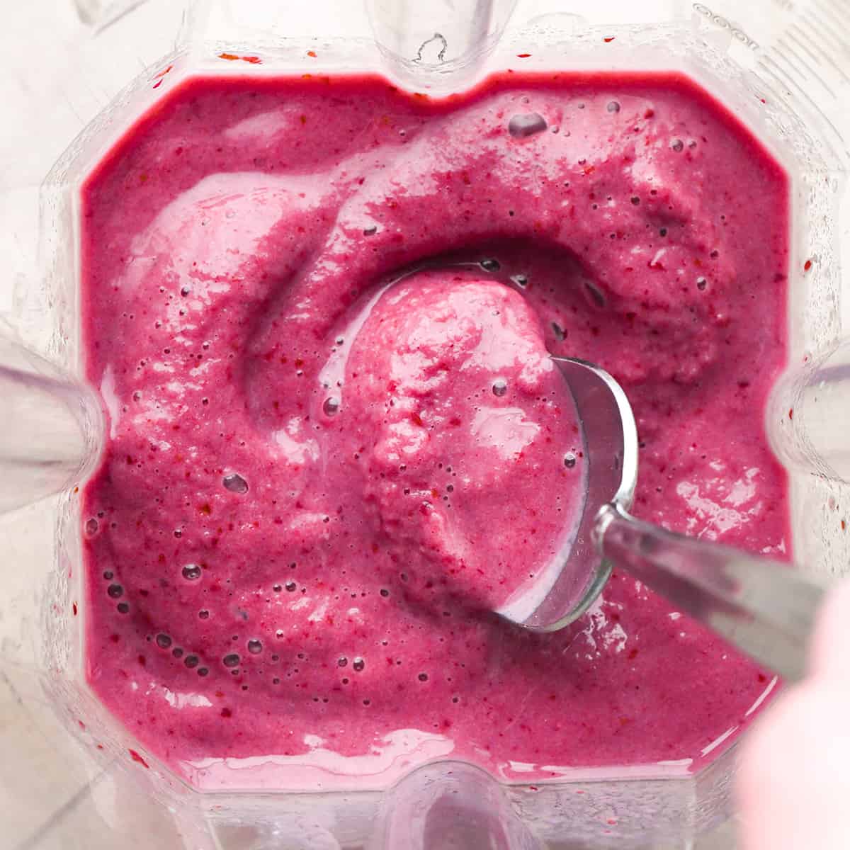 Cherry Smoothie ingredients in a Vitamix blender after blending with a spoon