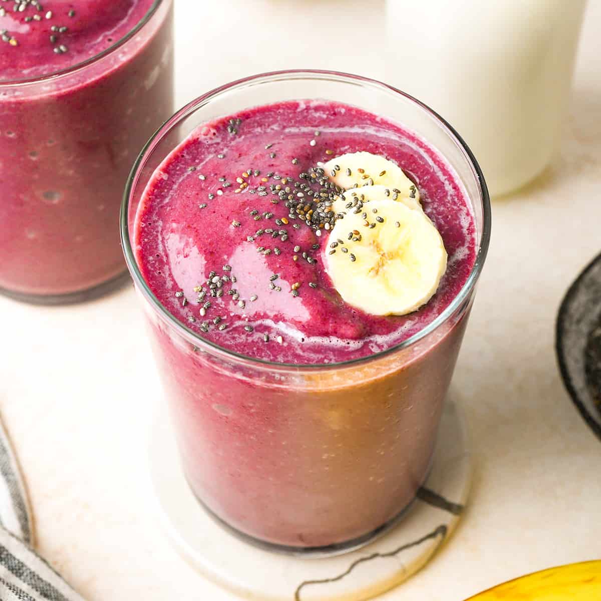 Cherry Smoothie in a glass topped with chia seeds and sliced bananas