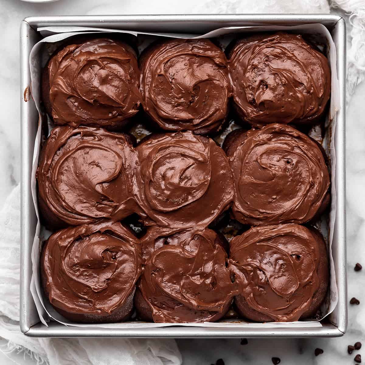 9 Chocolate Cinnamon Rolls in a baking pan with chocolate frosting