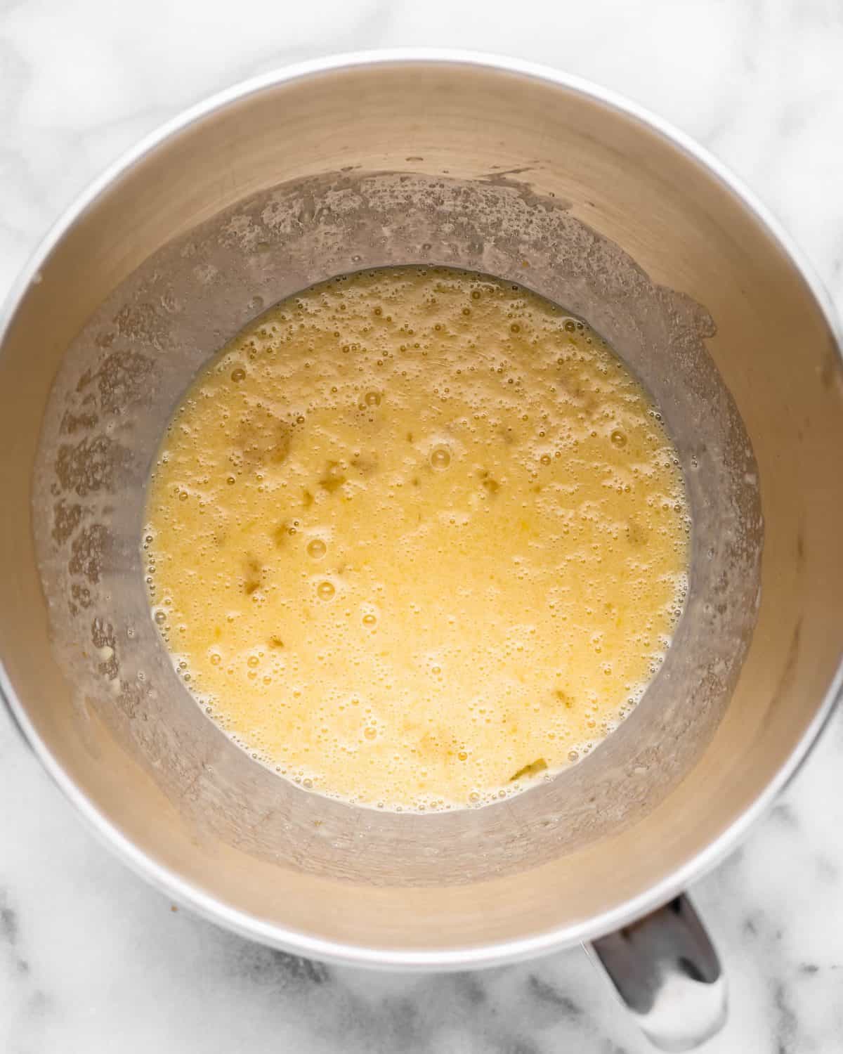 making chocolate cinnamon rolls - wet ingredient mixture in a metal mixing bowl on a marble surface after mixing.
