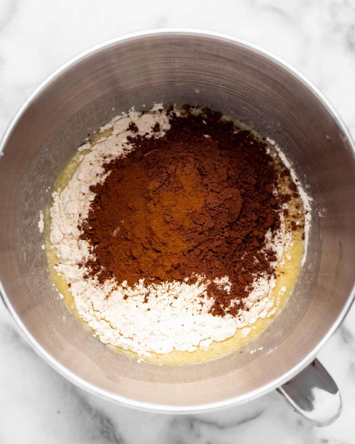 making chocolate cinnamon rolls - cocoa powder, flour and salt added to the wet ingredient mixture in a metal mixing bowl before mixing