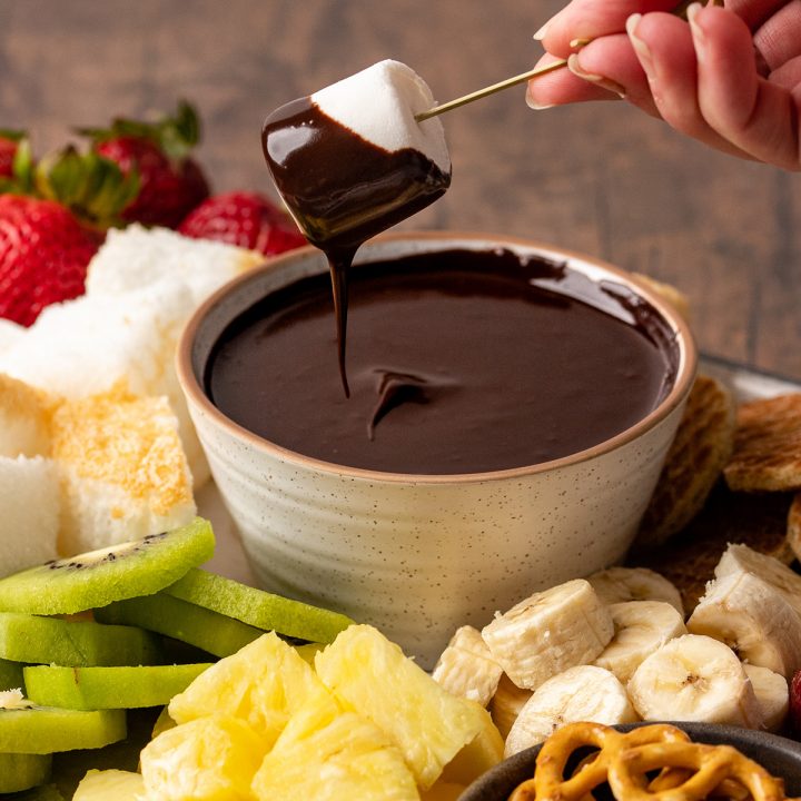 a marshmallow being dipped into a bowl of Chocolate Fondue