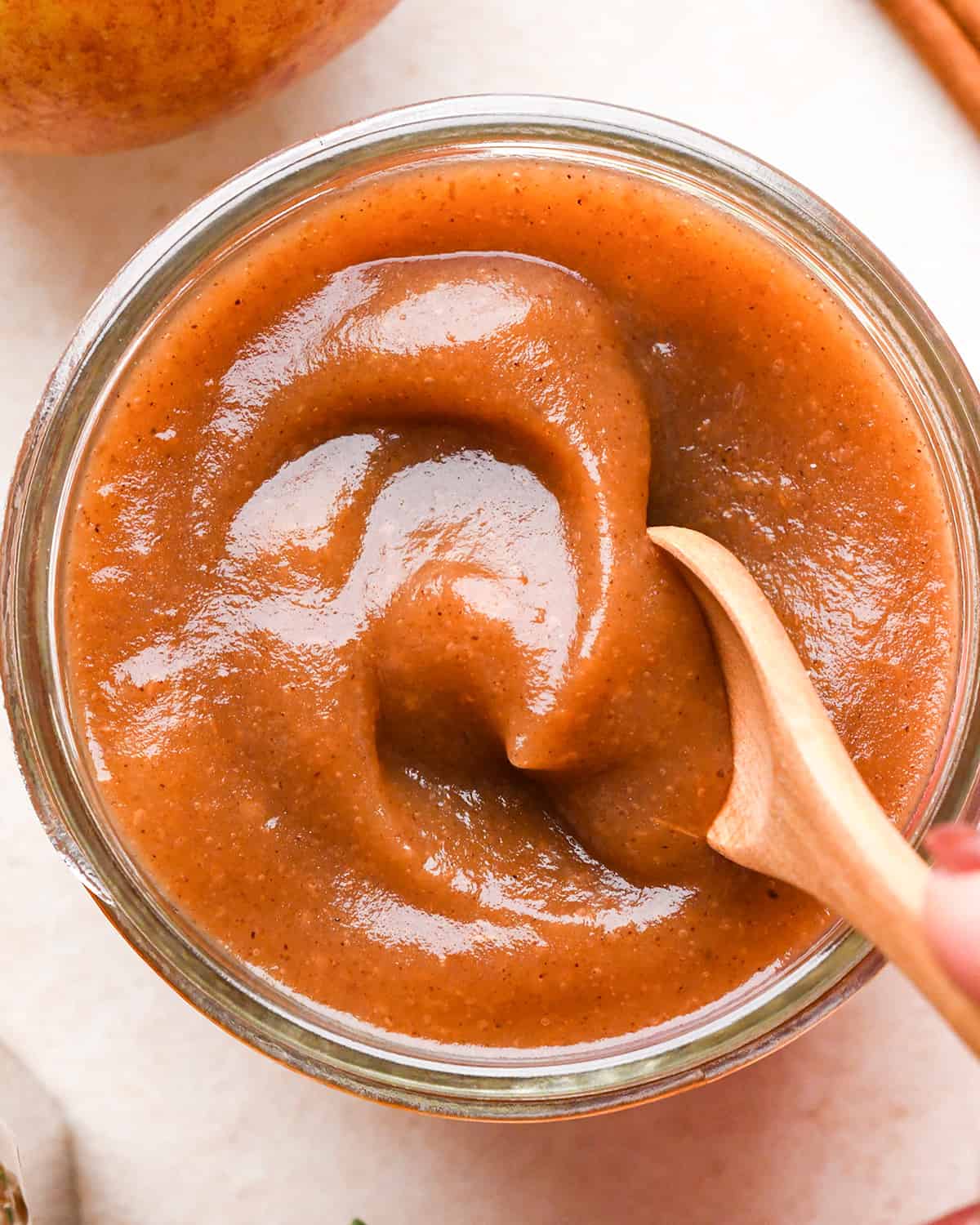 a spoon scooping Apple Butter out of a glass jar 