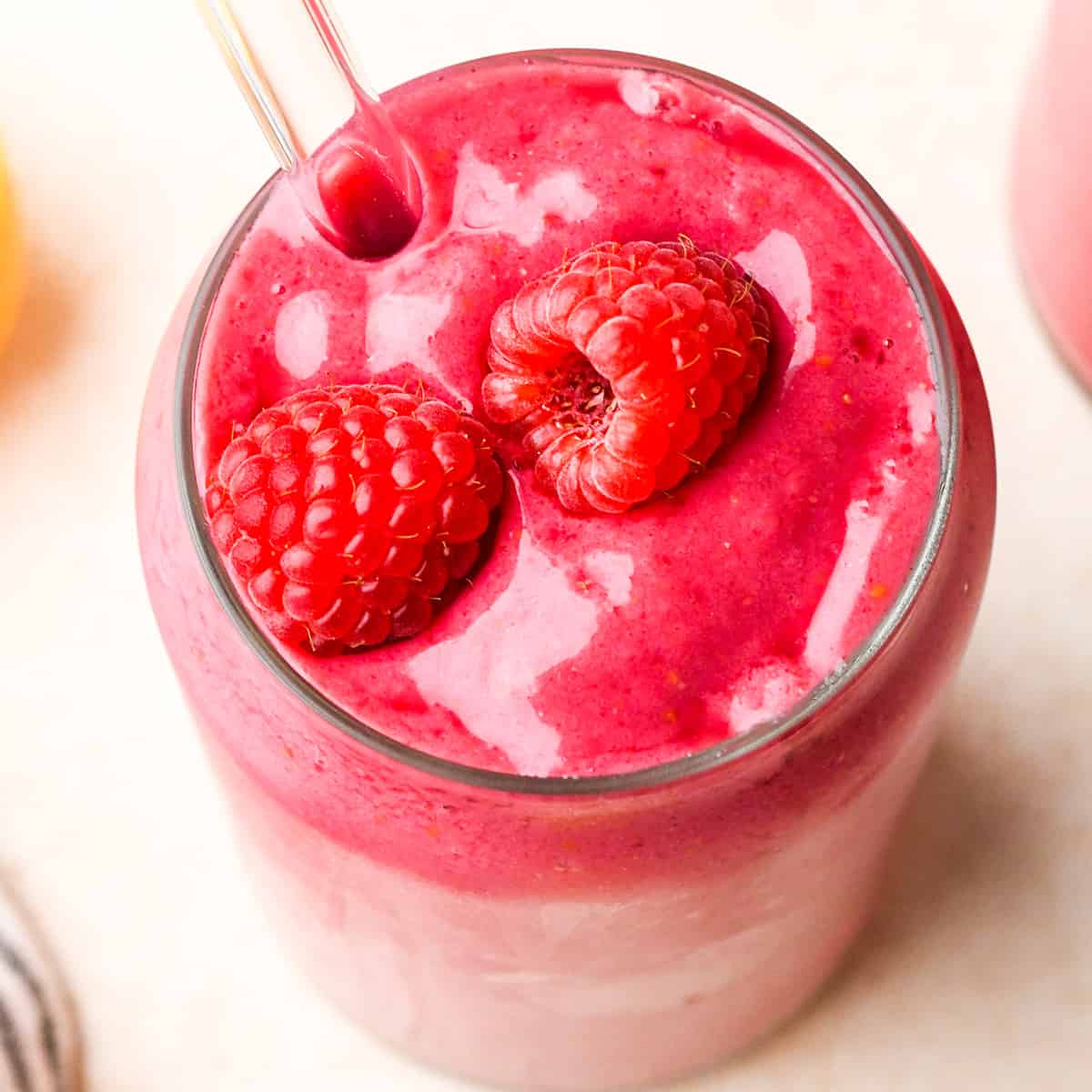 overhead photo of a Raspberry Smoothie in a glass topped with two raspberries