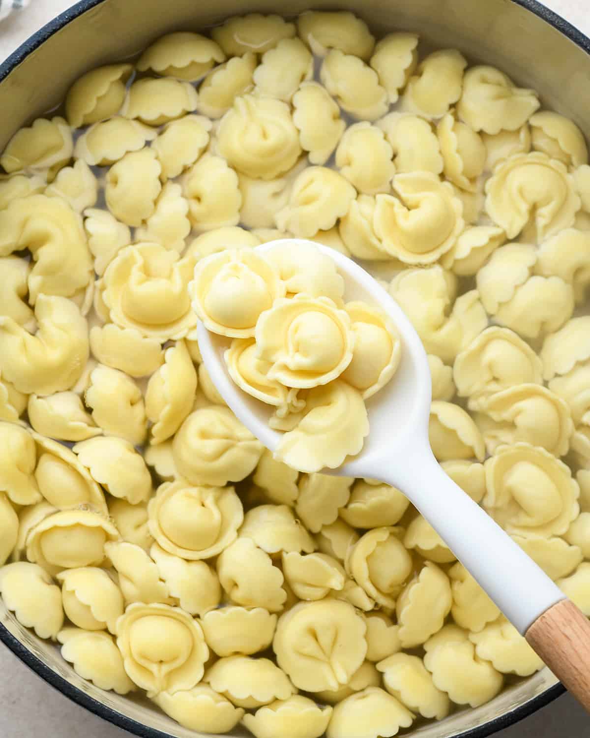 tortellini cooking in a pot with a spoon