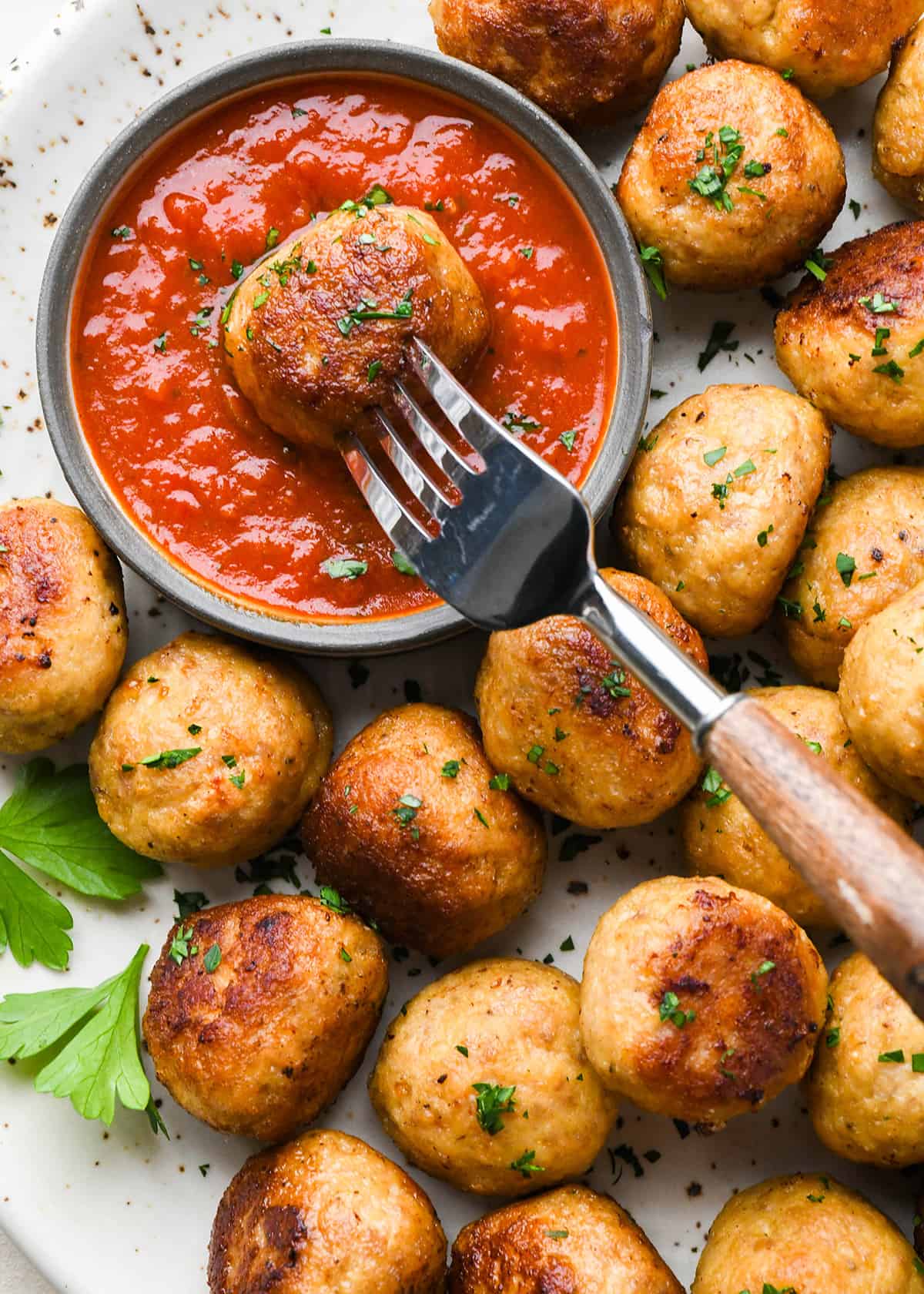 Chicken Meatballs being dipped into a bowl of marinara sauce with a fork