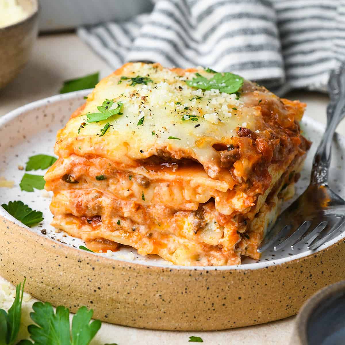a piece of Beef Lasagna on a plate with a fork