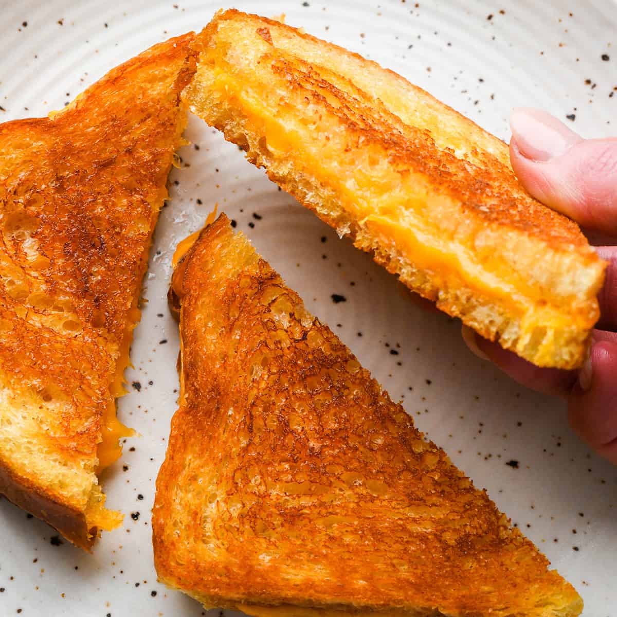 three halves of a grilled cheese sandwich on a plate