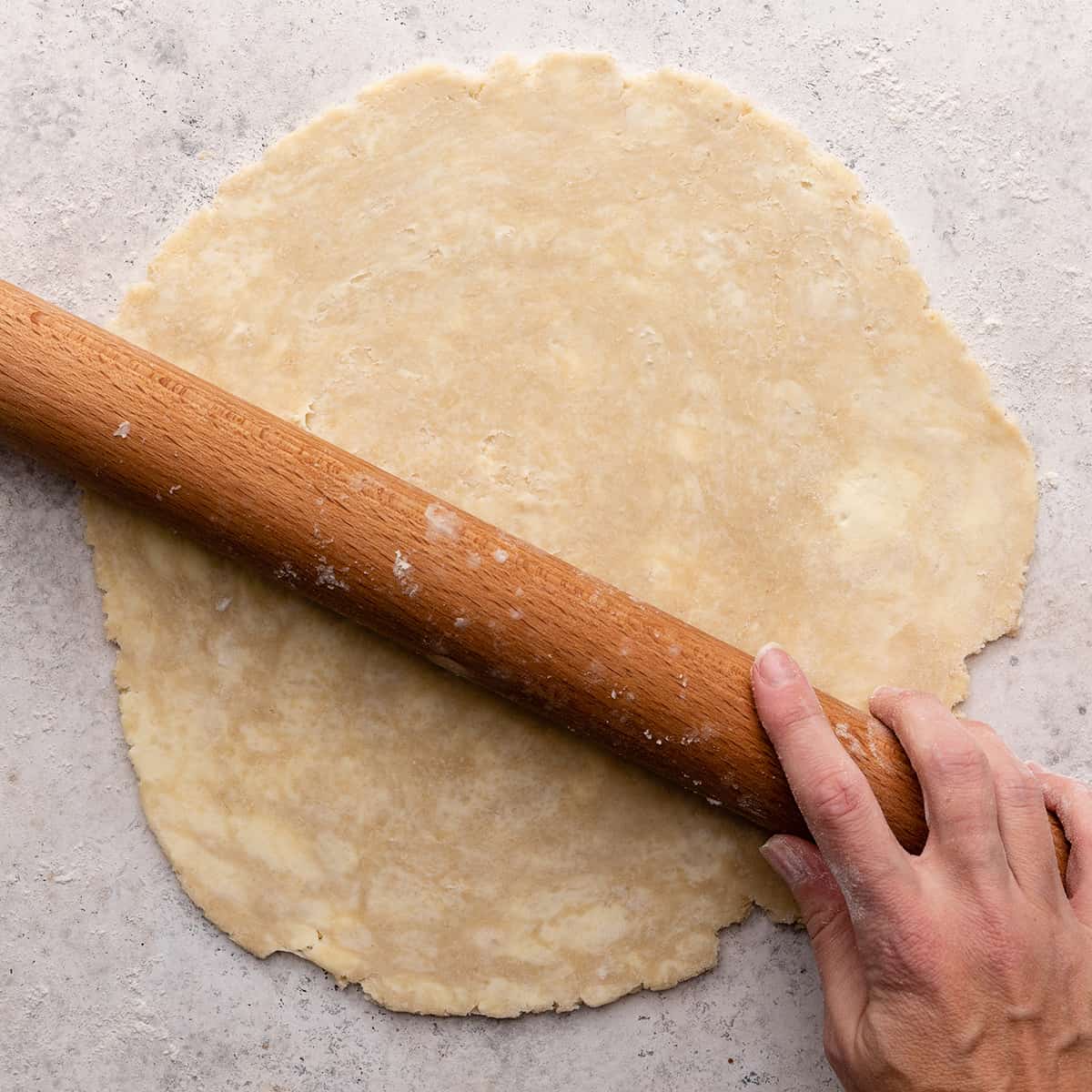 pie crust being rolled out with a wooden rolling pin