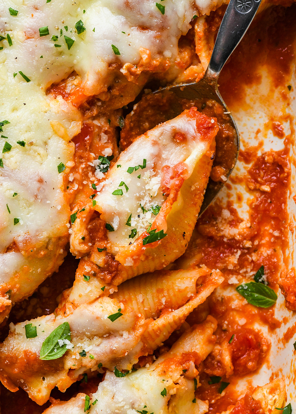 a spoon scooping Stuffed Shells out of a baking dish