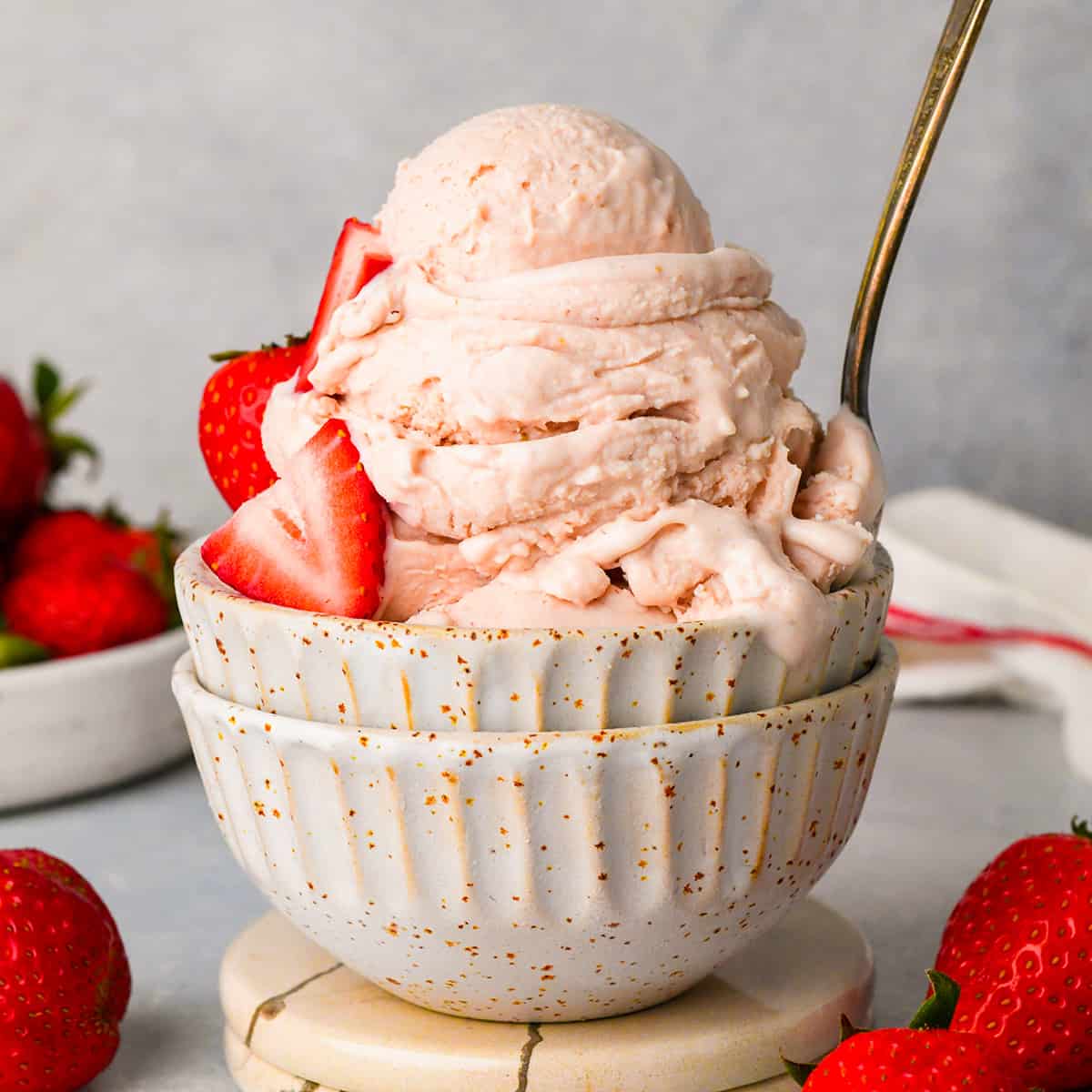 a bowl of Strawberry Ice Cream with fresh strawberries and a spoon