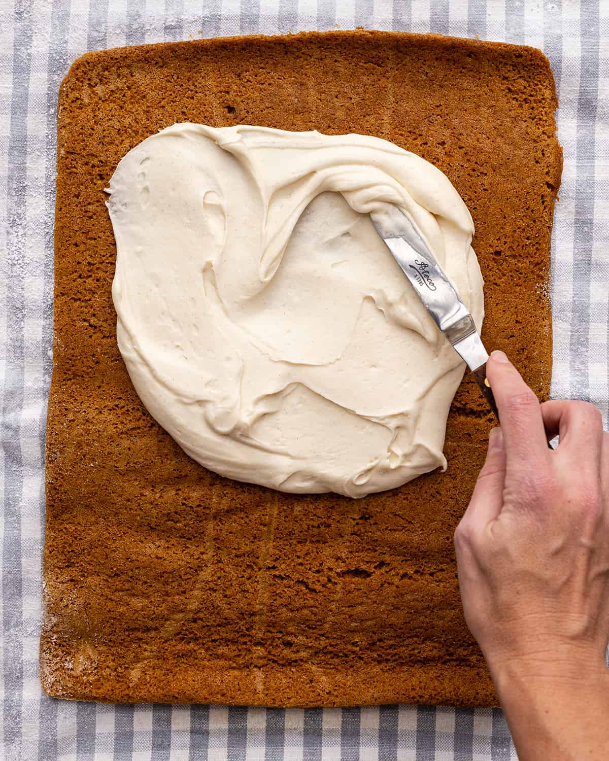 spreading the cream cheese frosting on to the Pumpkin Roll Cake
