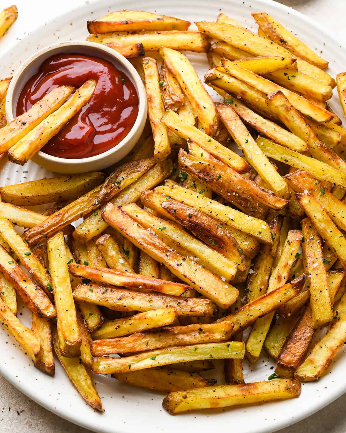 homemade french fries on a plate with a bowl of ketchup