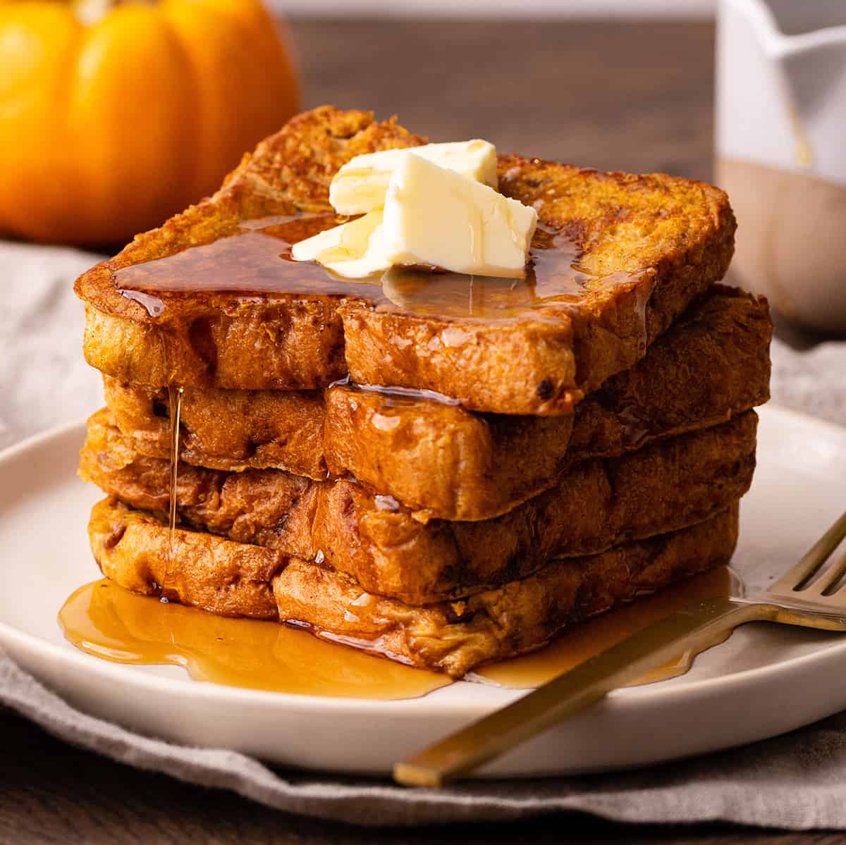 a stack of 4 slices of Pumpkin French Toast with butter and maple syrup