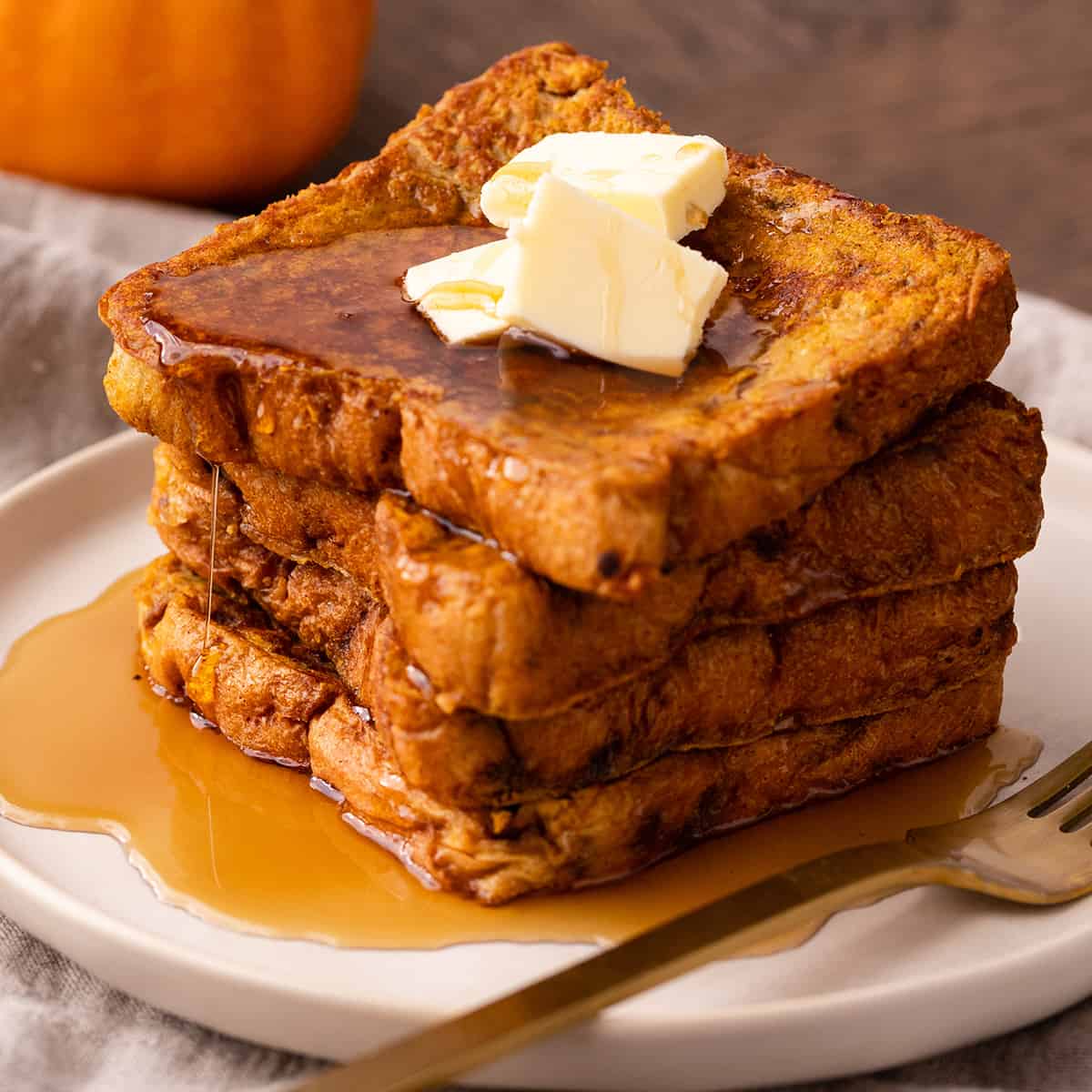 a stack of 4 slices of Pumpkin French Toast with butter and maple syrup