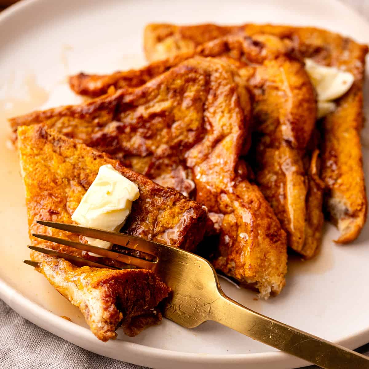 4 slices of Pumpkin French Toast on a plate with butter, syrup and a fork 