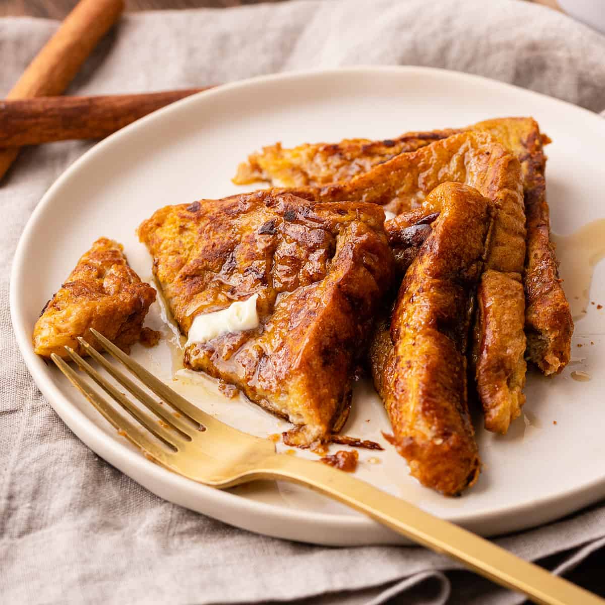 4 slices of Pumpkin French Toast on a plate with butter, syrup and a fork 
