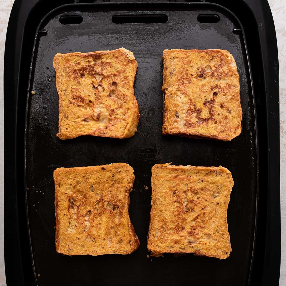 4 pieces of Pumpkin French Toast cooking on an electric griddle