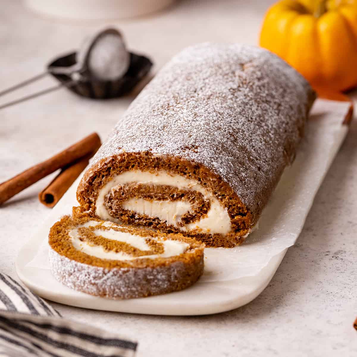 Pumpkin Roll Cake with a slice cut out of it