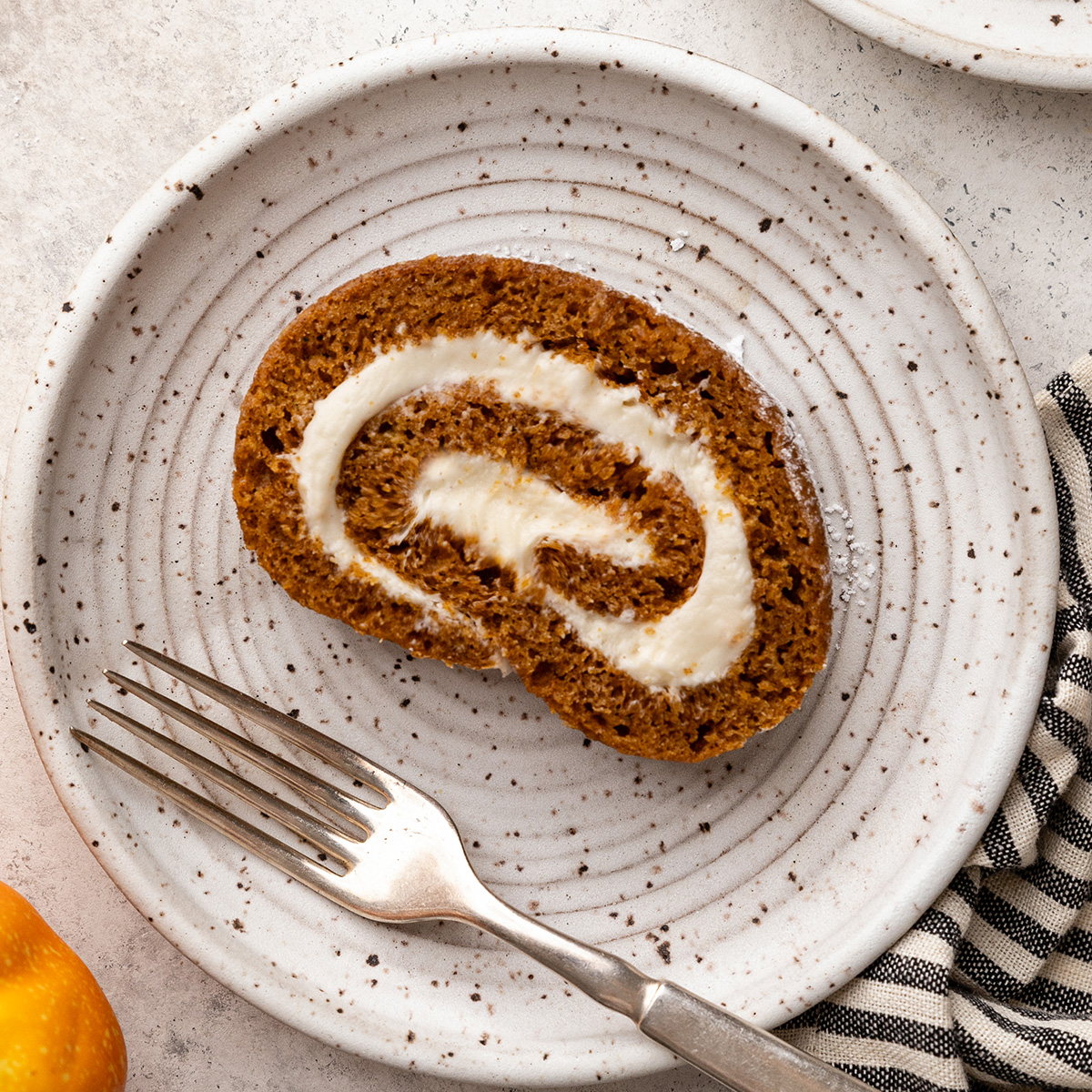 a slice of Pumpkin Roll Cake on a plate with a fork 