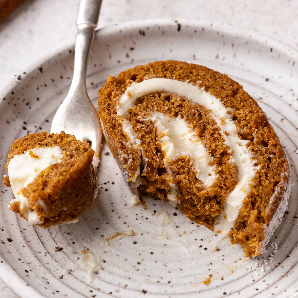 a slice of Pumpkin Roll Cake on a plate with a fork