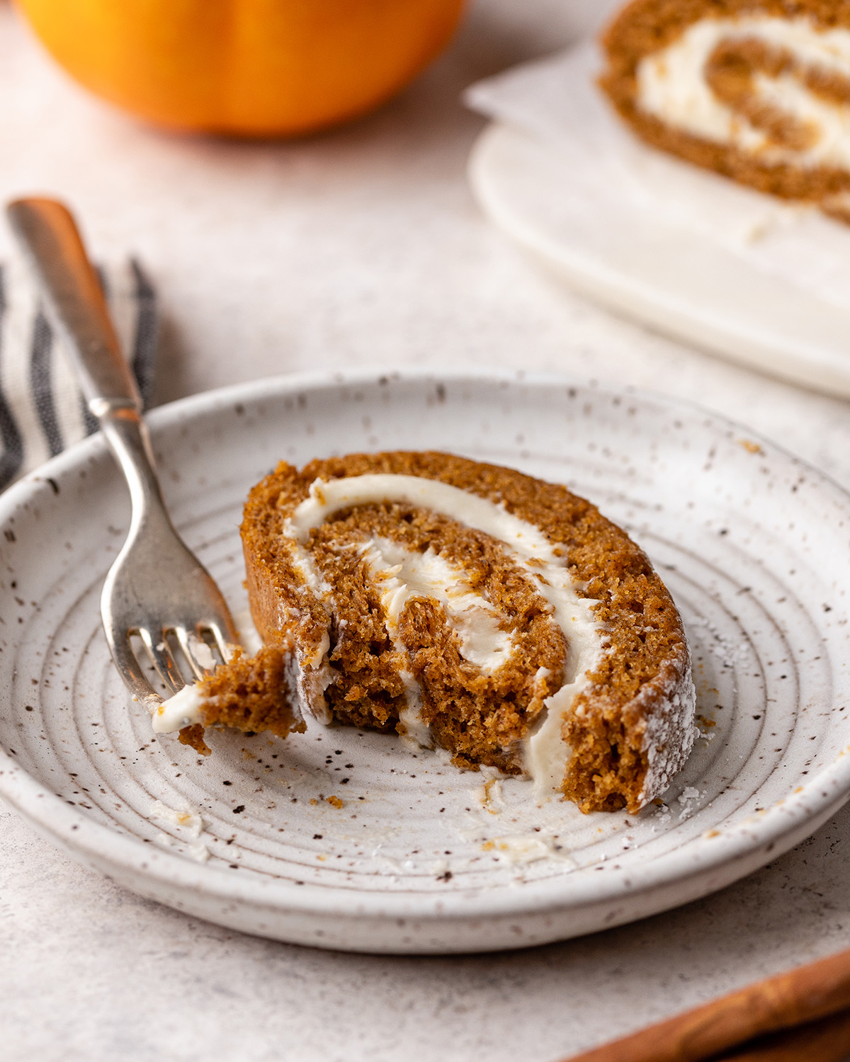 a slice of Pumpkin Roll Cake on a plate with a fork 
