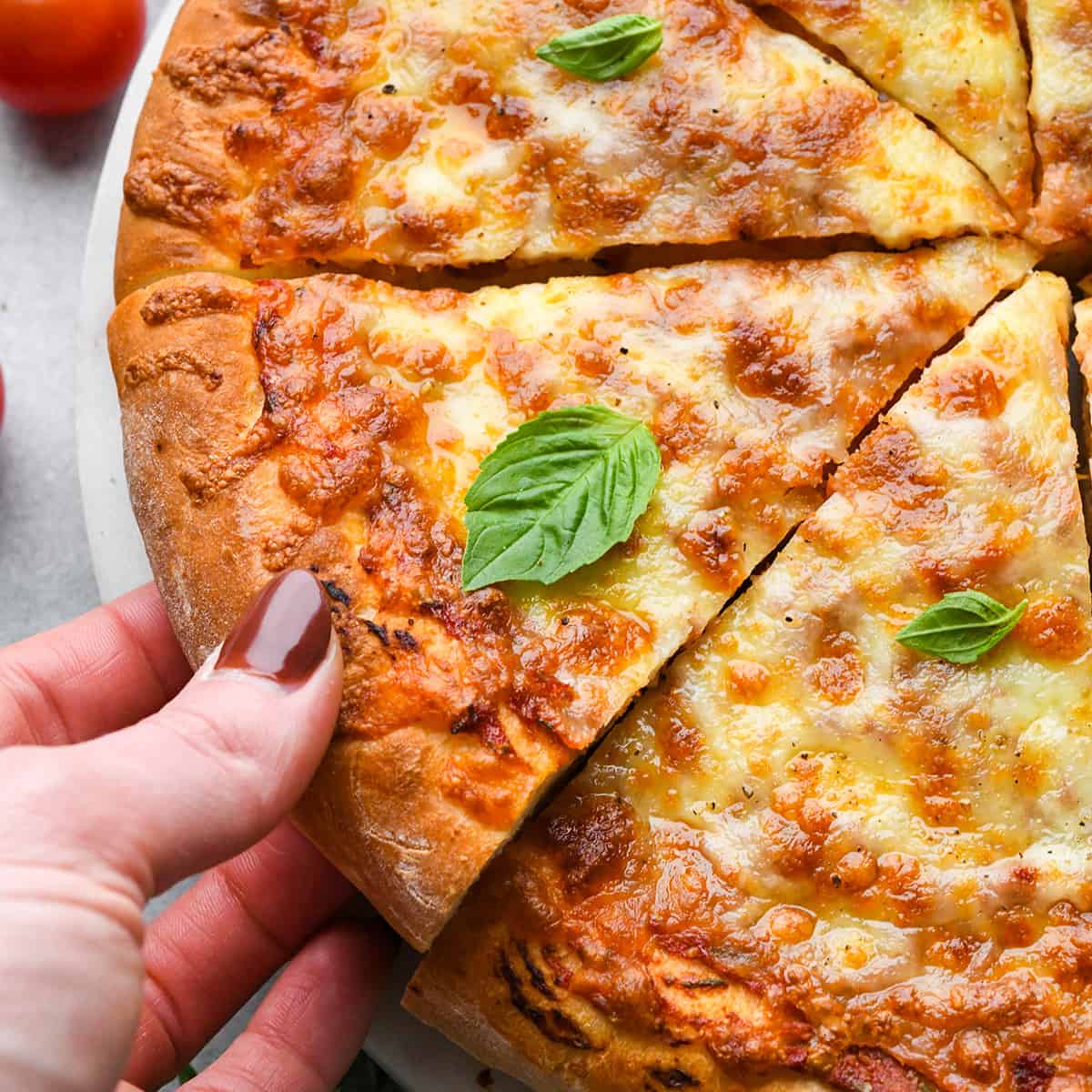 a hand taking a slice of pizza made with this Pizza Dough Recipe