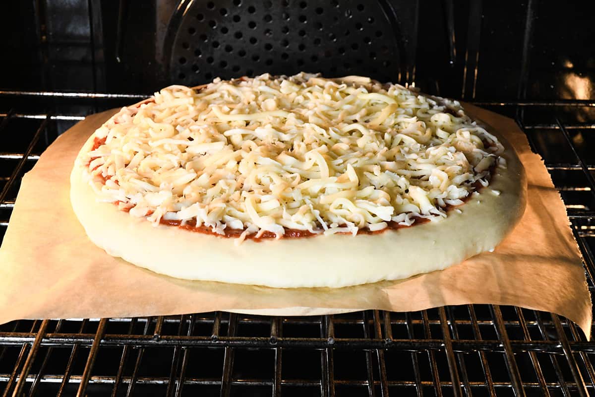 homemade pizza recipe baking on a pizza stone in the oven right after being put in