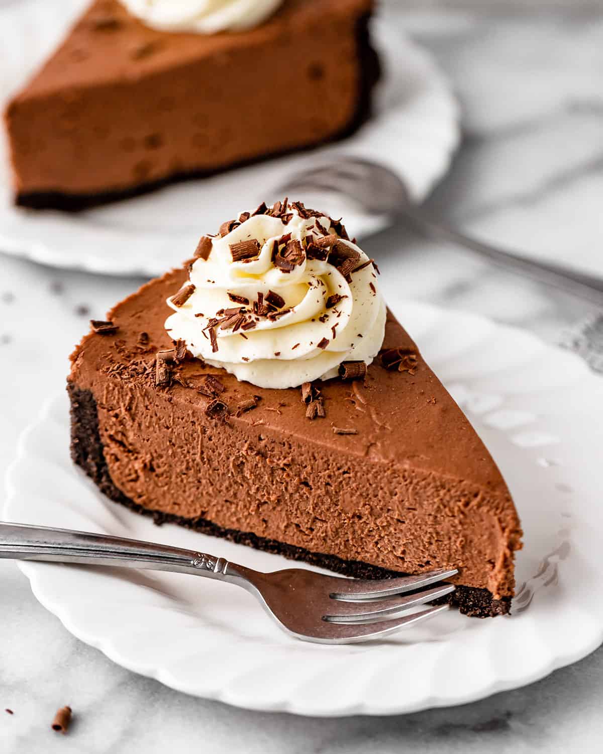 a slice of No Bake Chocolate Cheesecake on a plate with whipped cream and chocolate shavings 