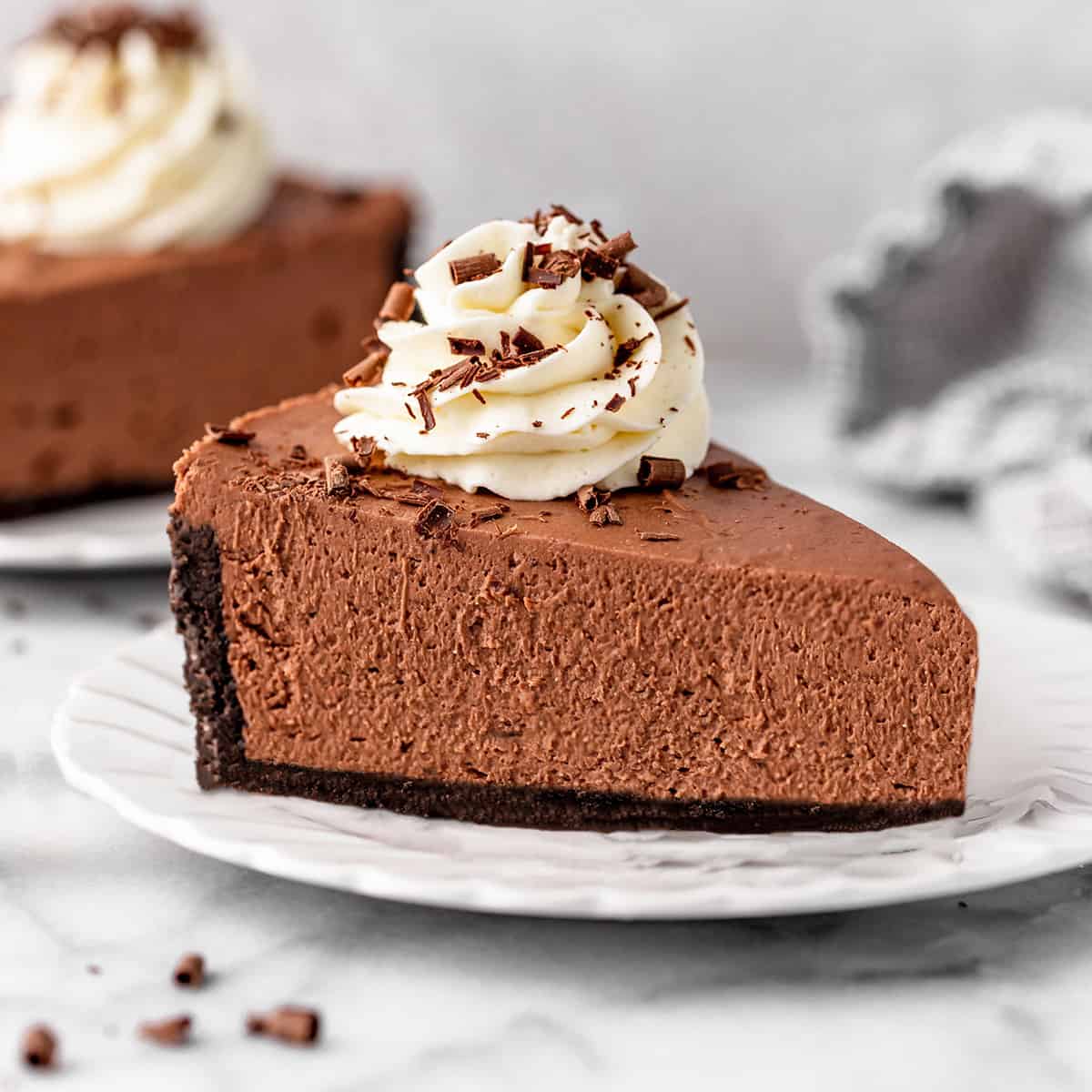 a slice of No Bake Chocolate Cheesecake on a plate with whipped cream and chocolate shavings