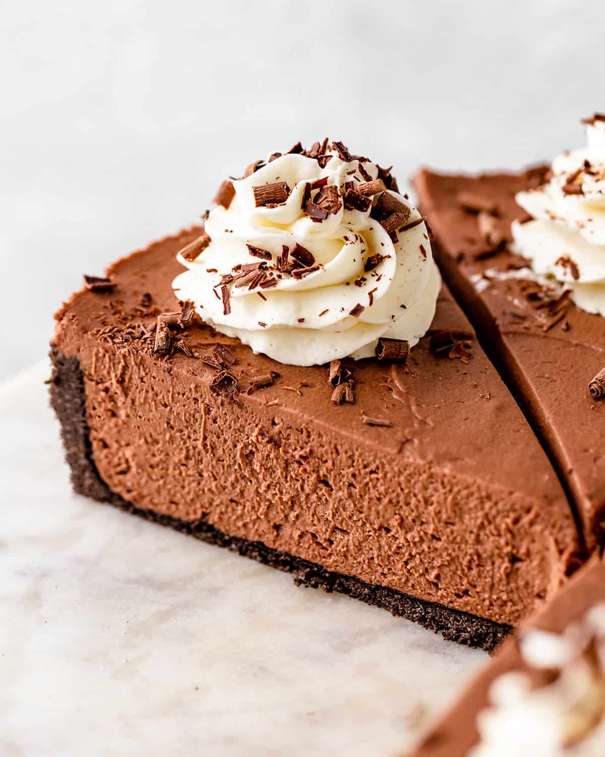 a slice of No Bake Chocolate Cheesecake topped with whipped cream and chocolate shavings 