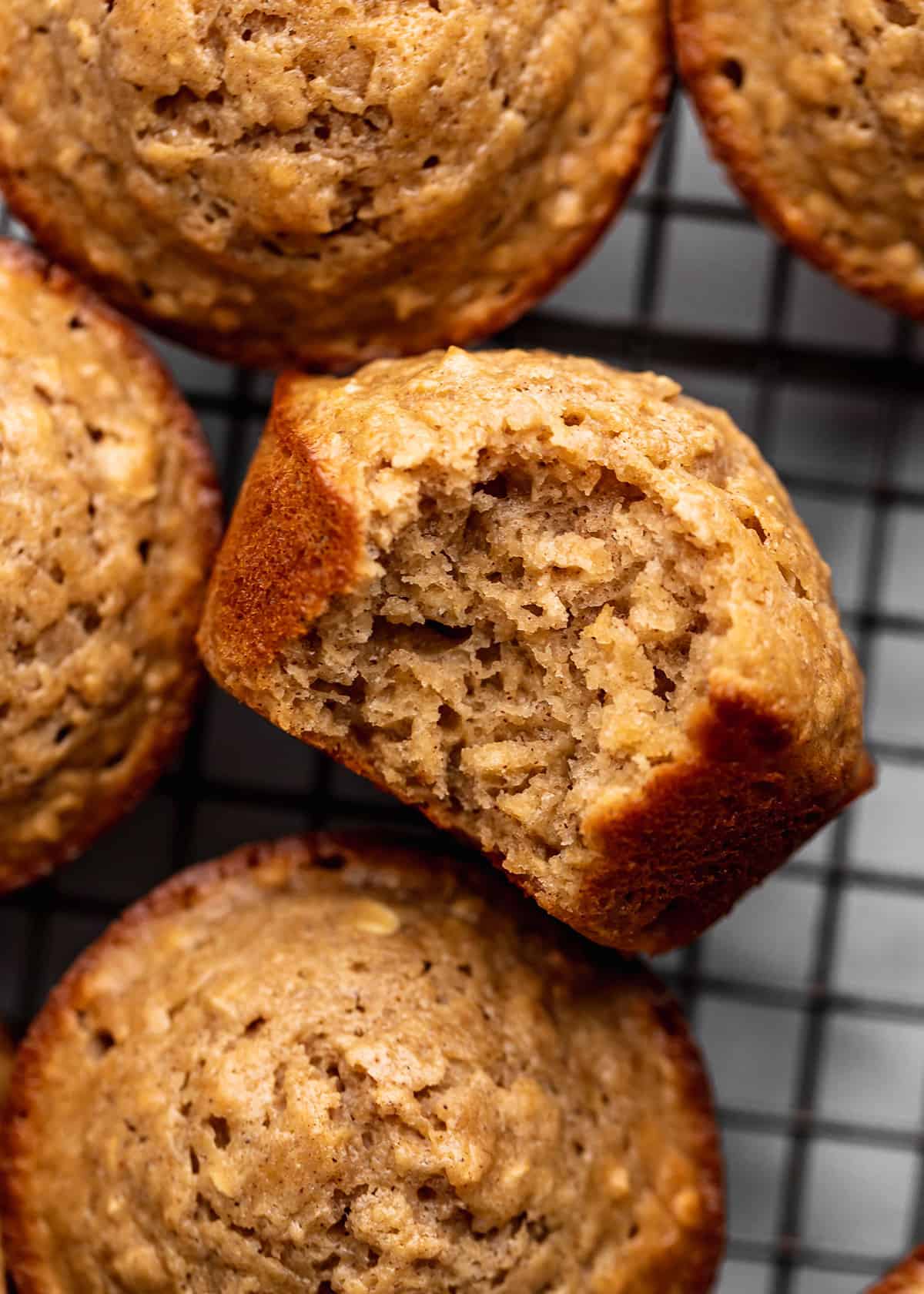 Oatmeal Muffins on a cooling rack, one has a bite taken out of it