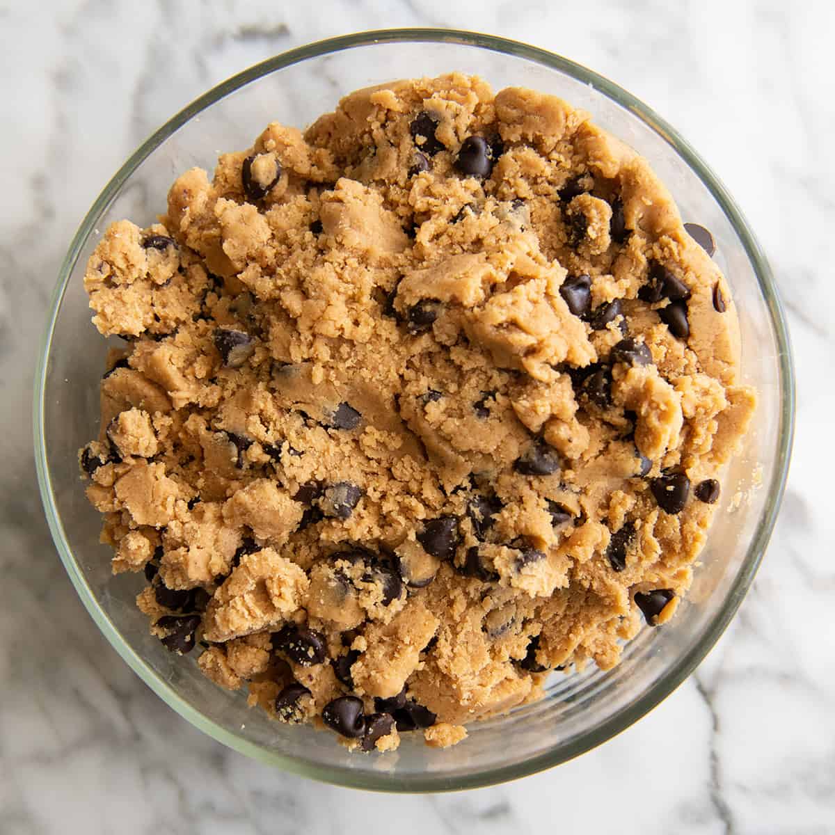Peanut Butter Chocolate Chip Cookie dough in a glass container to chill