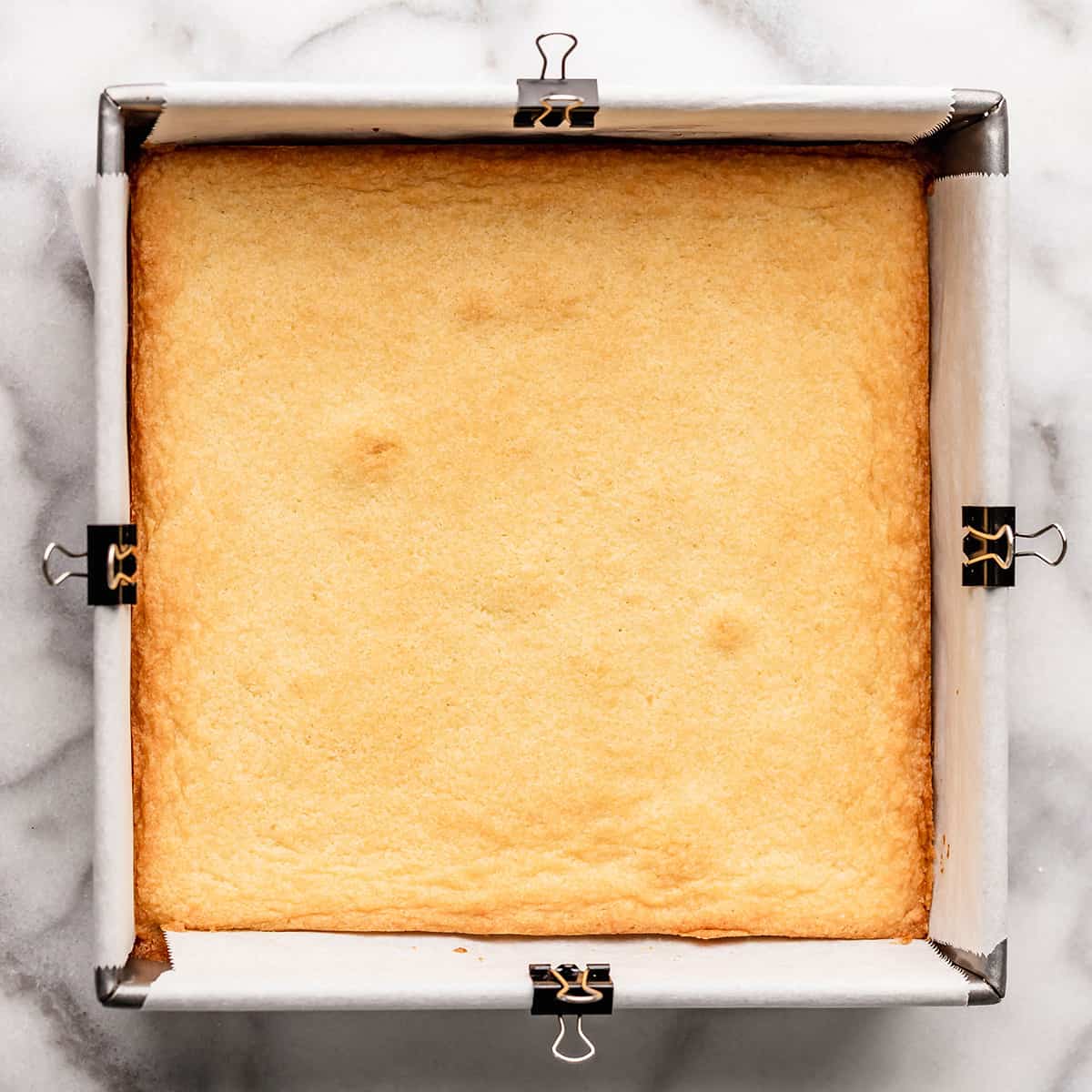 sugar cookie bar dough in an 8" baking pan before baking