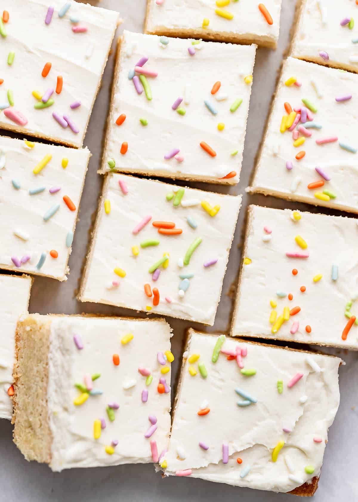 11 Sugar Cookie Bars cut into square topped with frosting and sprinkles