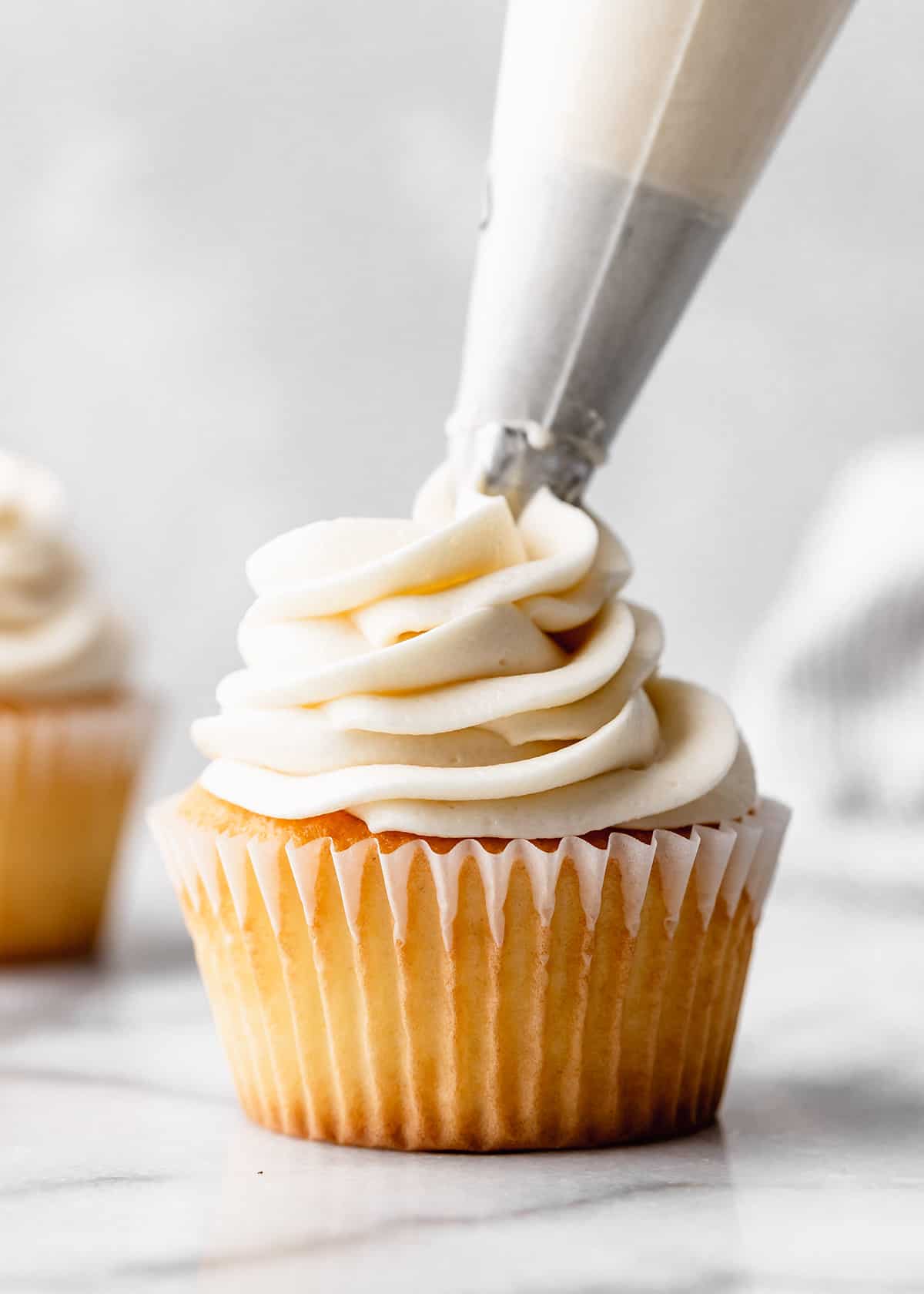two photos showing How to Make Buttercream Frosting - beating butter, vanilla and salt