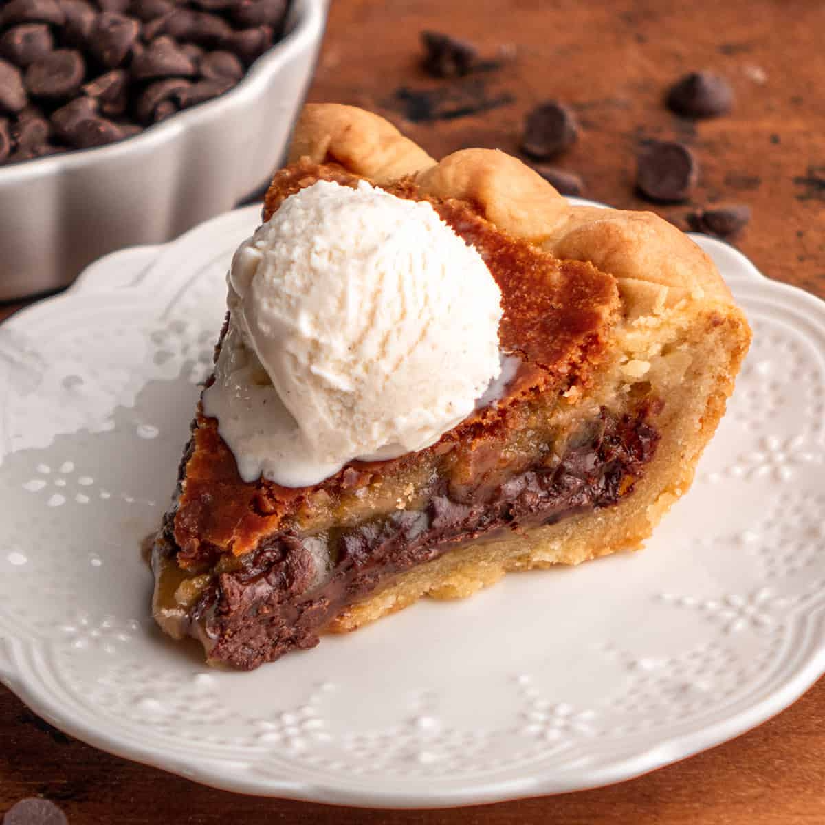 a sice of Chocolate Chip Cookie Pie on a plate with a scoop of vanilla ice cream