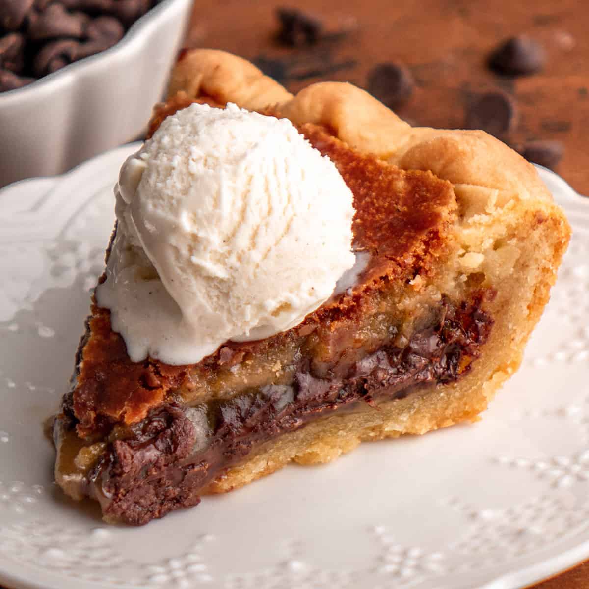a slice of Chocolate Chip Cookie Pie on a plate with vanilla ice cream