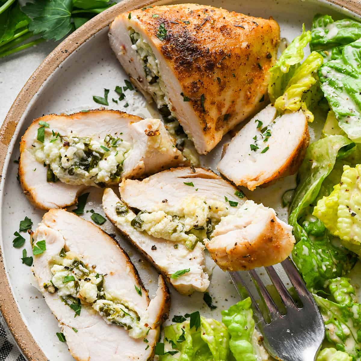 Spinach Stuffed Chicken Breasts on a plate with 4 piece cut from it