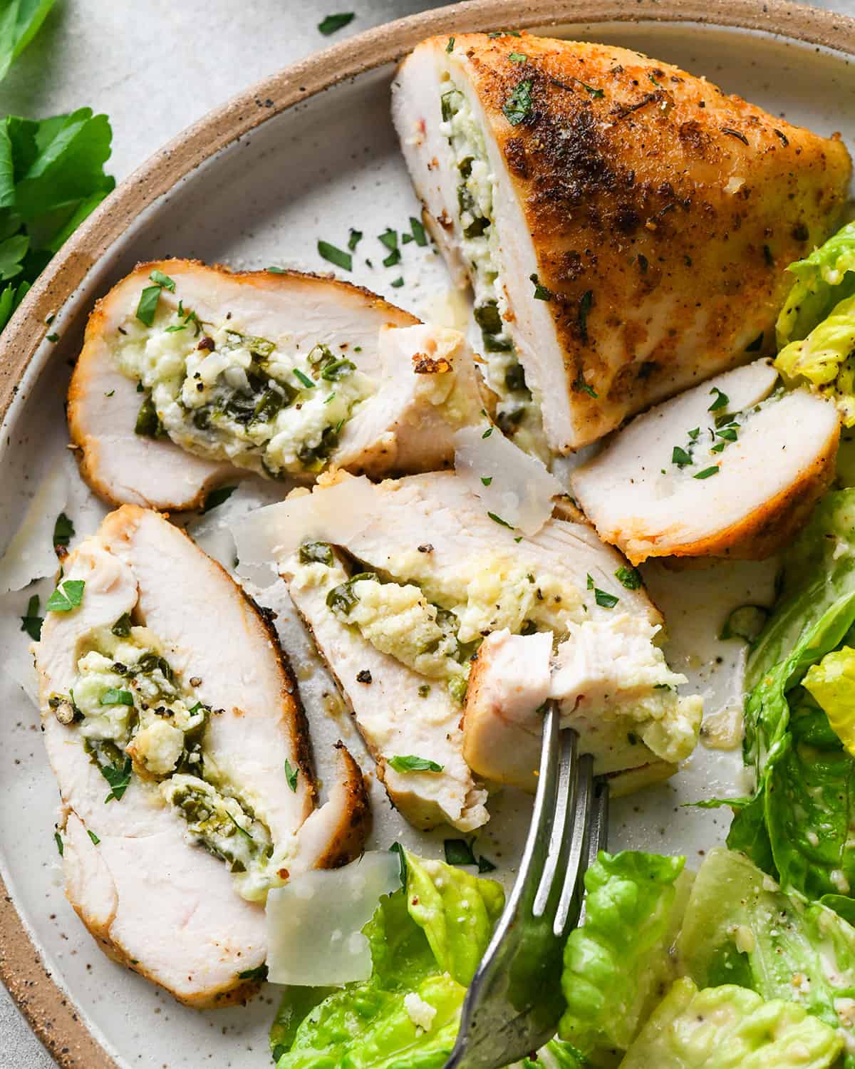 Spinach Stuffed Chicken Breast on a plate with 4 pieces cut out of it