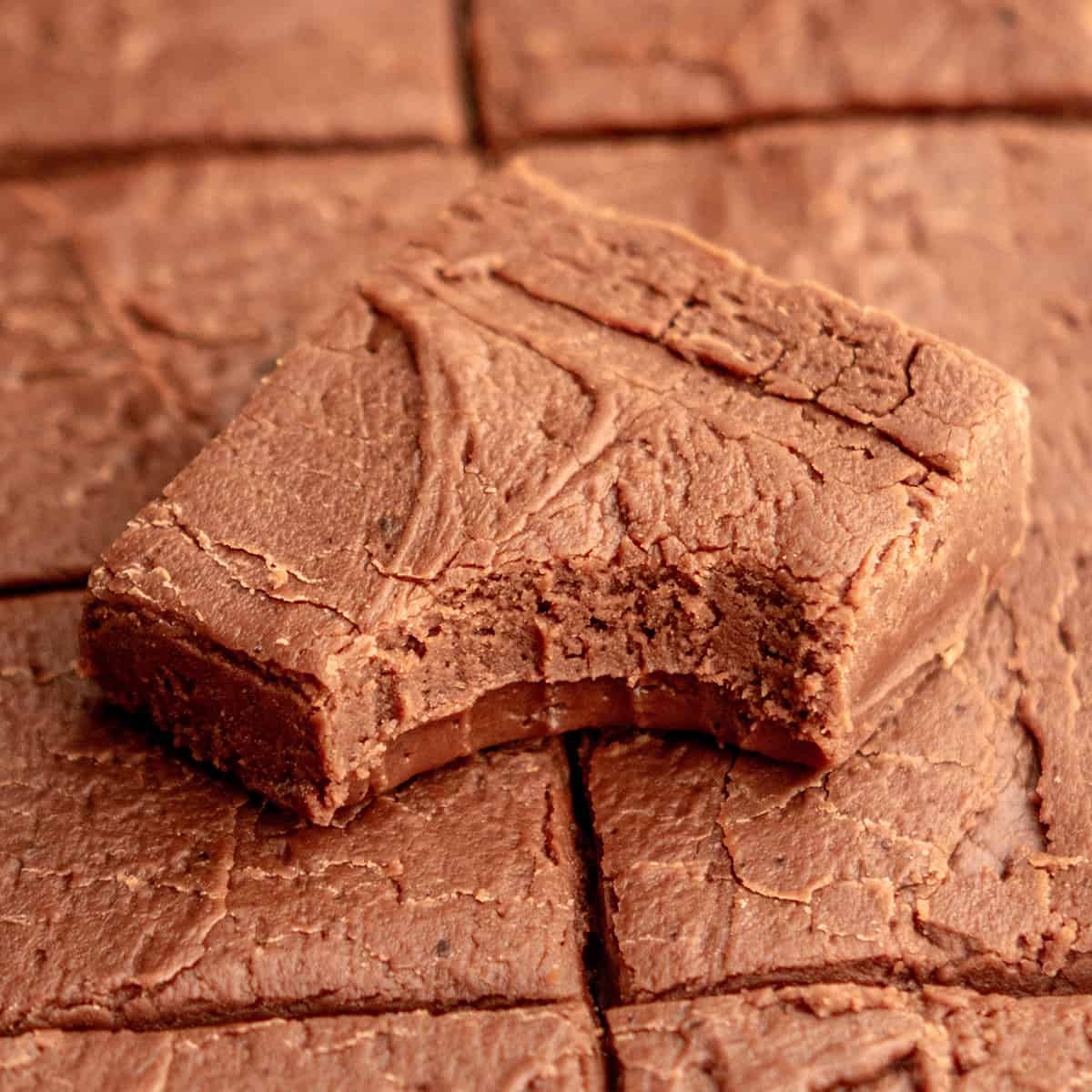 a piece of chocolate fudge with a bite taken out of it on top of other pieces of fudge