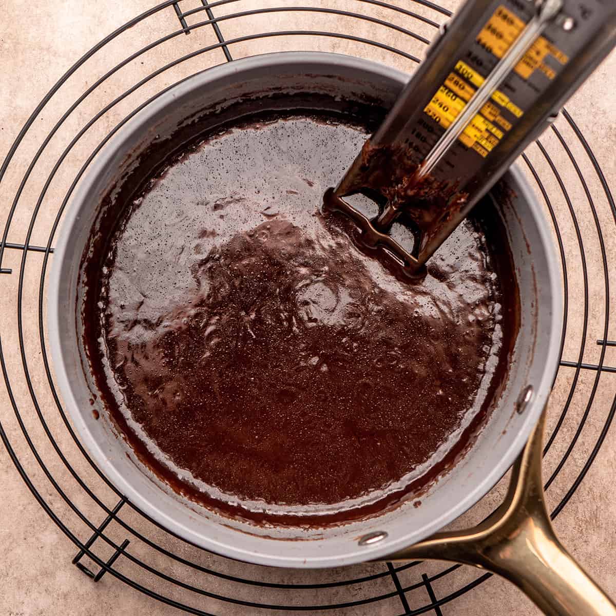 a candy thermometer inside chocolate fudge mixture in a saucepan