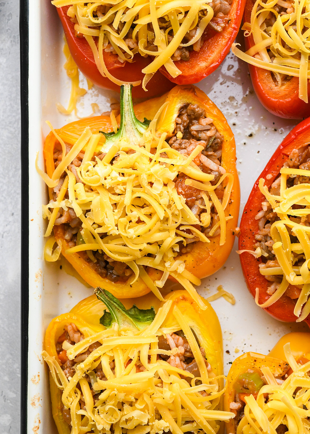 stuffed peppers on a baking sheet topped with cheese before baking