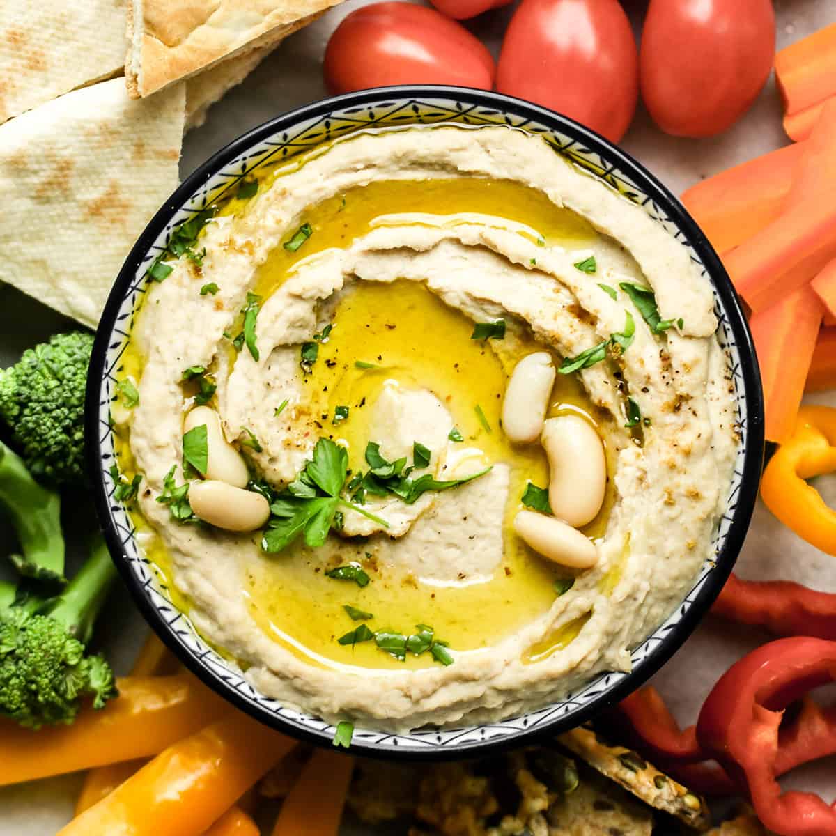 a bowl of White Bean Hummus surrounded by veggies and pita bread