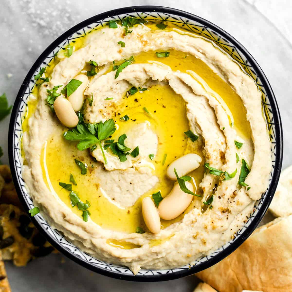 a bowl of White Bean Hummus garnished with parsley and olive oil