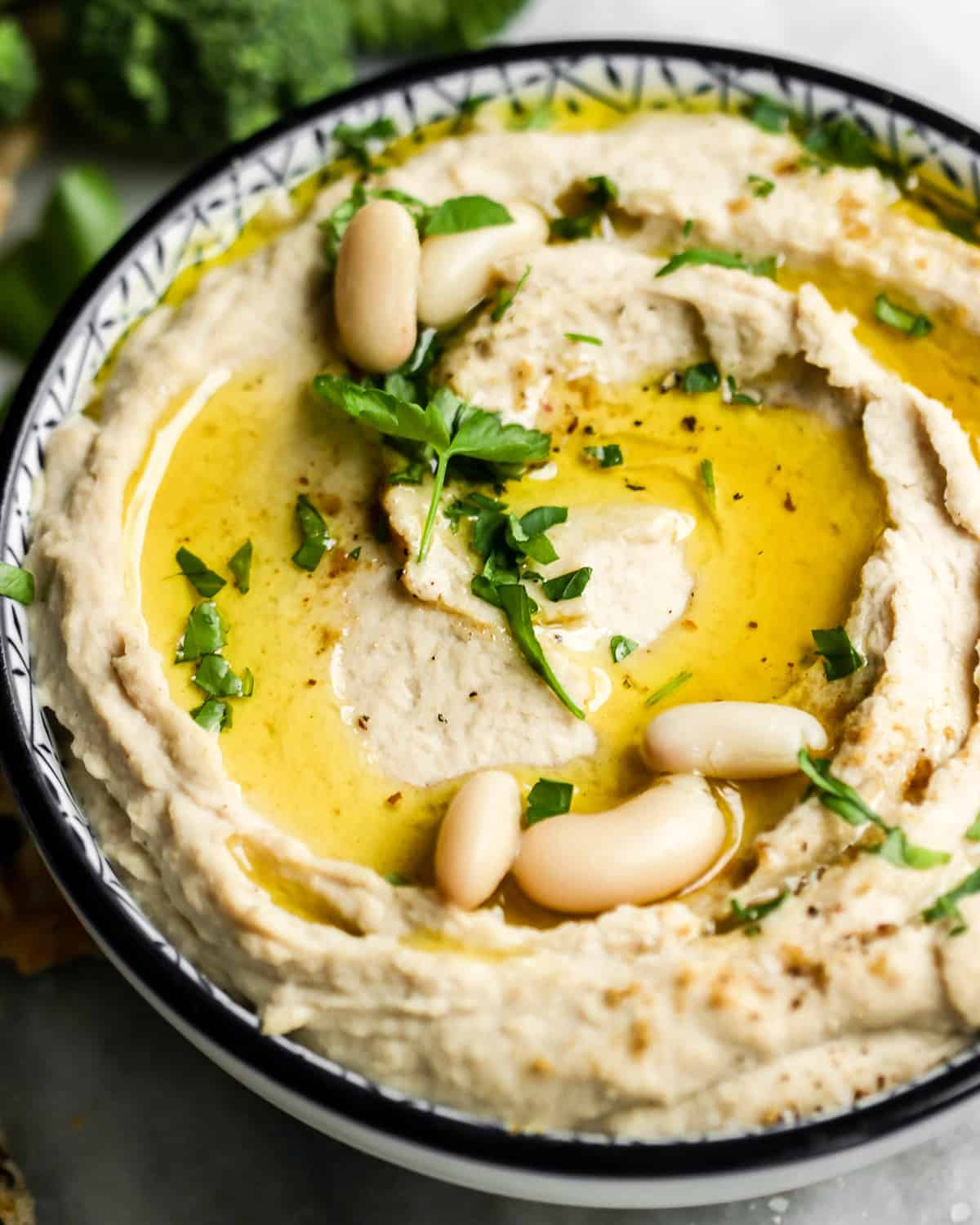 a bowl of White Bean Hummus garnished with parsley and olive oil